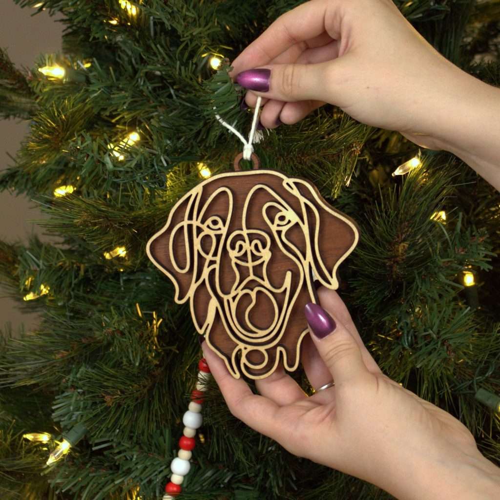 dog breed ornament shown in hands of the maker, being applied to Christmas tree