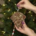dog breed ornament shown in hands of the maker, being applied to Christmas tree