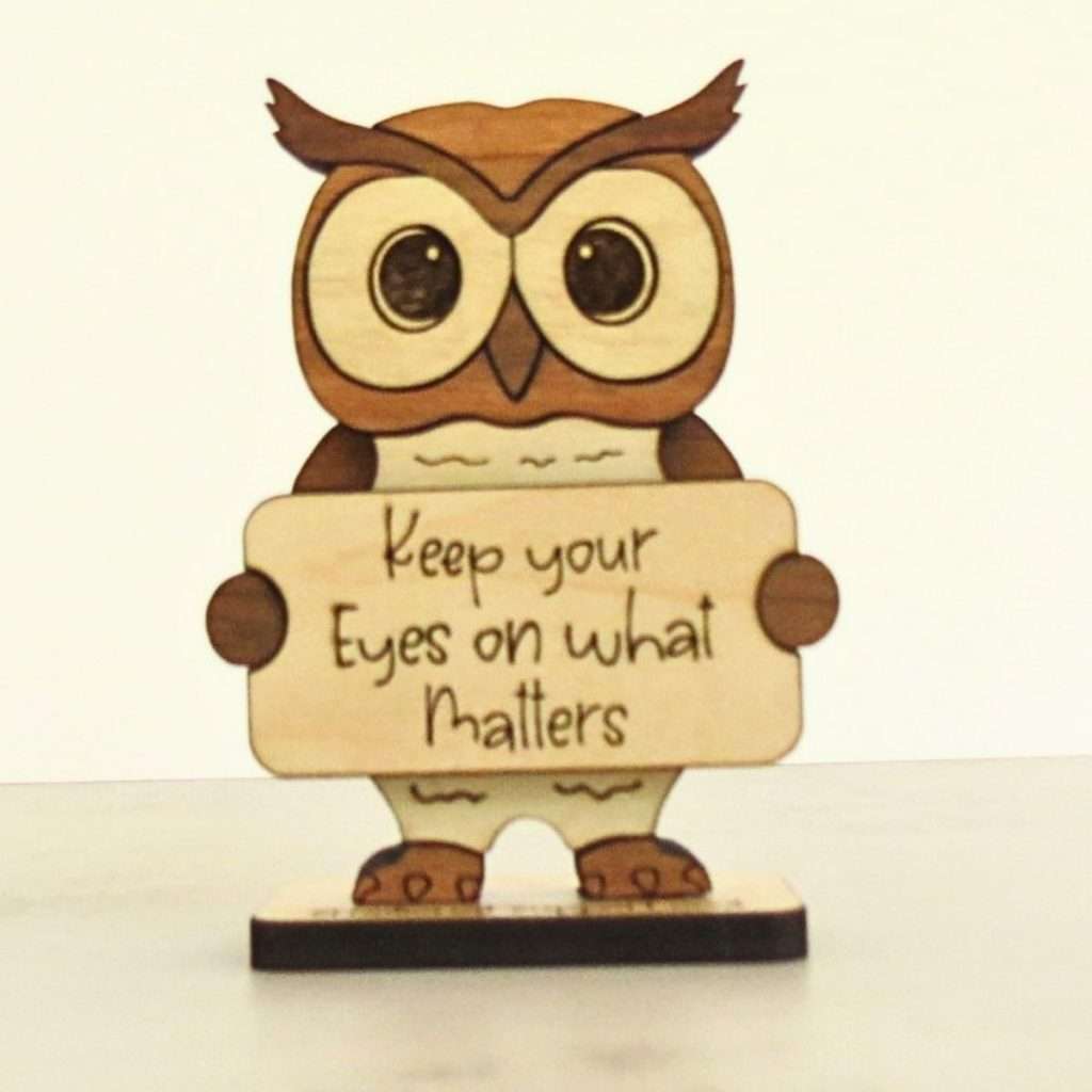 Handcrafted hardwood emotional support owl desk pet holding sign that reads Keep Your Eyes on What Matters
