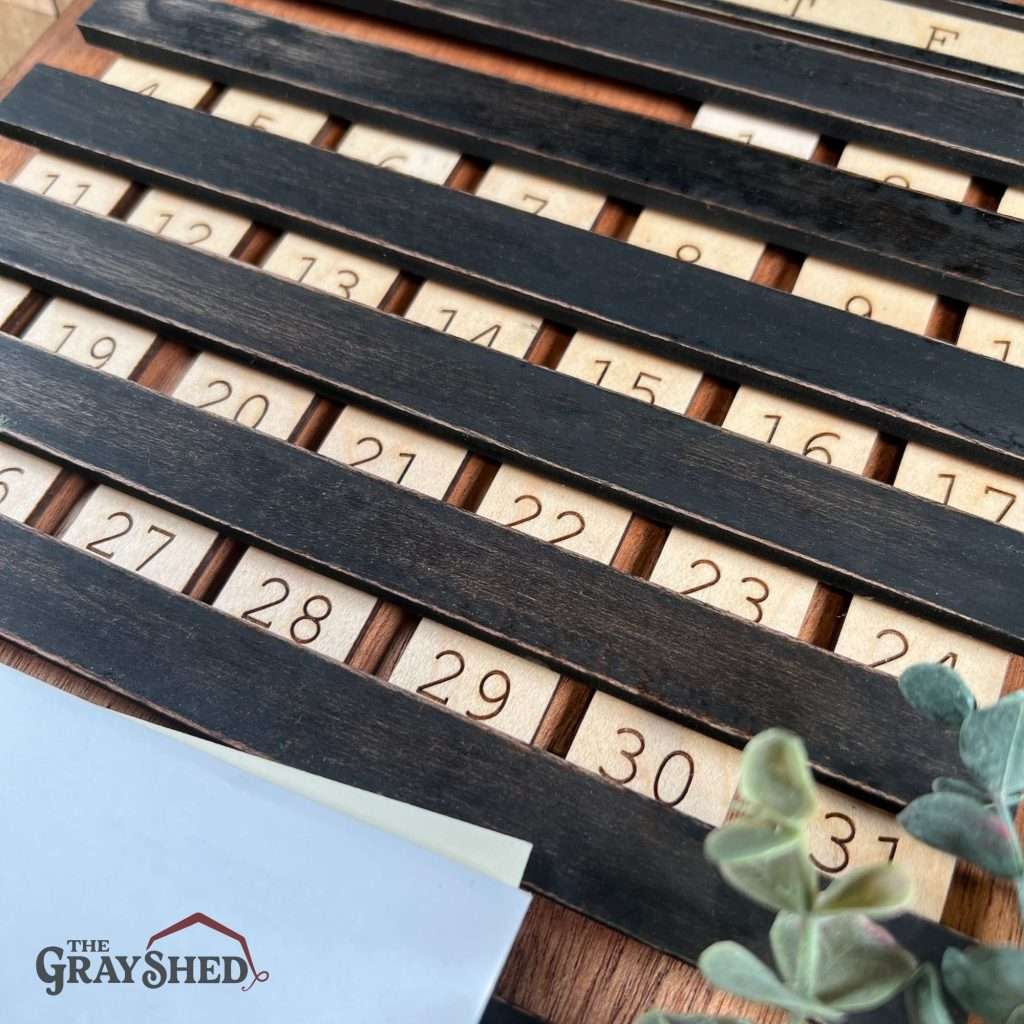 Vintage style perpetual calendar, close up view of the slide-in days of the month in their tracks.