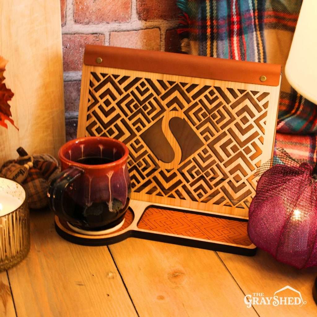 Geometric monogram book stand, shown in the light stain and leather combination with the letter S cutout in a styled scene with an attractive handmade coffee mug.