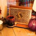 Geometric monogram book stand, shown in the light stain and leather combination with the letter S cutout in a styled scene with an attractive handmade coffee mug.
