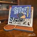 The rose design front book stand in use as a bookmark with a book positioned over it.